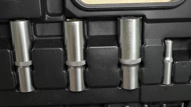 Close up of socket attachments for ratchet wrench in tool case, automotive repair, threaded connections and mechanical work.