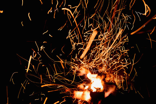 Fire embers particles over black background. Fire sparks background. Abstract dark glitter fire particles lights.