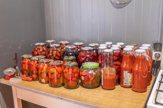 Canned homemade tomatoes and organic juice in glass jars on table