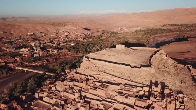 Aerial view of the historic Kasbah of Ait Benhaddou with earthen buildings, surrounding desert landscape, and river in Ait Benhaddou, Draa-Tafilalet, Morocco.