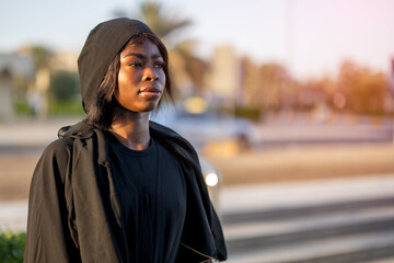 Profile portrait of a young black Muslim woman wearing a black hijab outdoors © Bojan