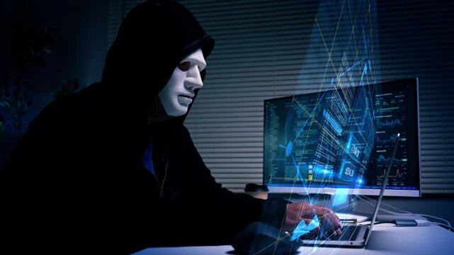 Anonymous hacker wearing mask sitting at desk with laptop and monitor in dark room. cybersecurity concept for it security campaigns, data breach prevention, and technology blogs.	