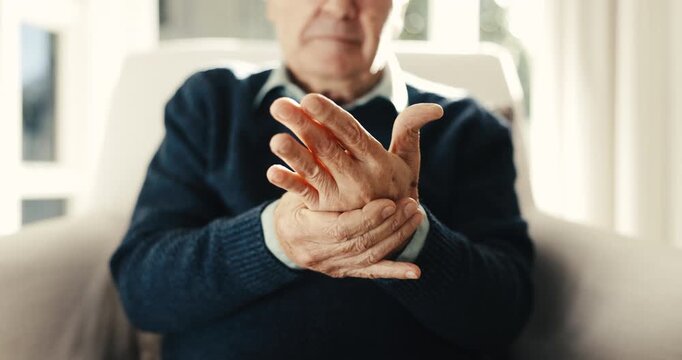 Arthritis, old man or hands in house with massage, joint tension or discomfort in muscle pain. Retirement, tendinitis and elderly person with ache, chronic condition and osteoporosis in living room.