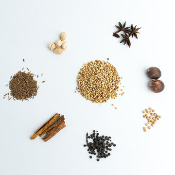 Assortment of dry cooking spices including cinnamon star anise coriander and nutmeg isolated on white