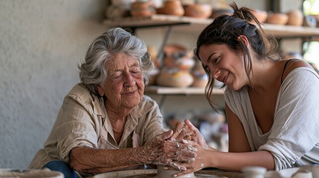 Artisane senior transmettant un savoir-faire en c&eacute;ramique &agrave; une jeune
