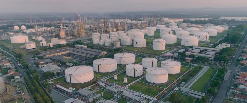 Aerial view of oil refinery with numerous white storage tanks and industrial infrastructure in Cilacap Regency, Central Java, Indonesia.