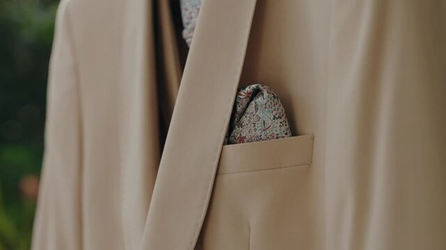 Patterned pocket square folded into the chest pocket of a beige tailored suit jacket