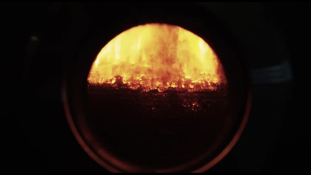 Fire burning inside sight glass of industrial biomass furnace