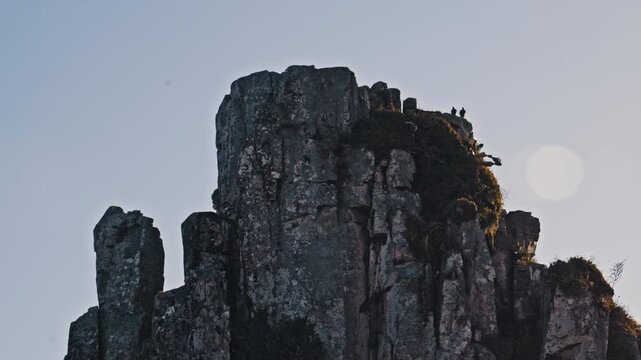 A static shot captures two ravens perched atop a rugged, mossy rock formation against a clear sky. This dramatic, atmospheric clip is ideal for nature documentaries or cinematic storytelling.