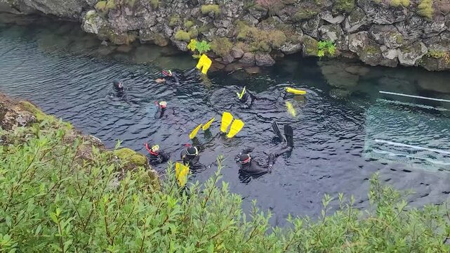 Snorkelers Swimming Through Clear Water Between Volcanic Rocks in Iceland