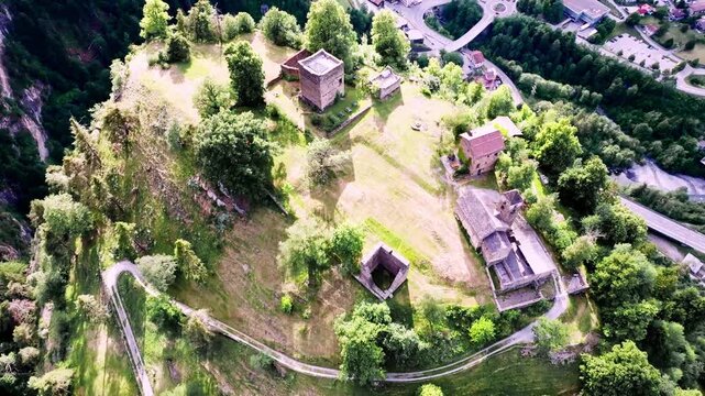 Aerial view of the historic stone ruins of Burg Hohen Ratien situated on a lush green hilltop with winding paths and surrounding forest in Sils im Domleschg, Grisons, Switzerland.