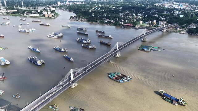 Aerial view of Karnaphuli 3rd Bridge spanning the river with numerous cargo ships and barges navigating the waterway in Chittagong, Chittagong Division, Bangladesh.