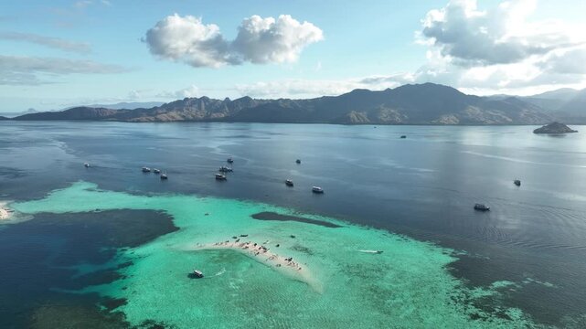 Aerial view of Taka Makasar sandbar surrounded by turquoise waters and boats in Komodo, East Nusa Tenggara, Indonesia.
