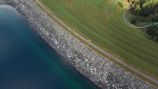 Aerial view of the Marmorera Dam reservoir with stone embankment and green grassy slopes in Surses, Grisons, Switzerland.