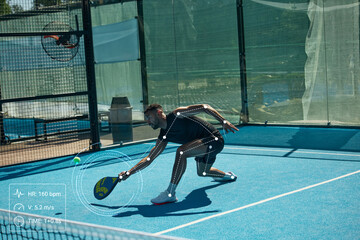 Fototapeta premium Male padel player reaching low ball with joint tracking and biometric performance data. Concept of padel coaching, body mechanics and injury prevention.