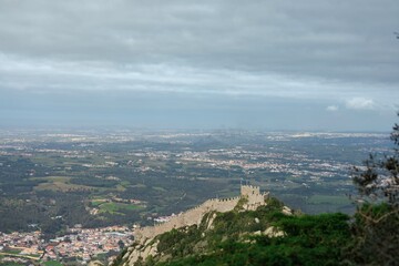 Perched atop a lush hillside, these ancient castle ruins command a sweeping view of a fertile valley and distant towns under a dramatic sky. Nature and history converge, inviting exploration © Damian