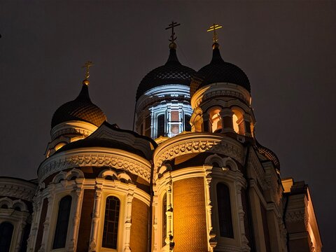 Low angle night view of illuminated onion domes and crosses of Alexander Nevsky Cathedral in Tallinn, Estonia.