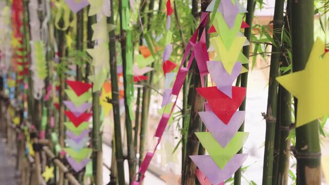 Vibrant paper ornaments and stars hanging from bamboo stalks for the Japanese Tanabata Star Festival. Traditional summer celebration decorations with a soft bokeh background and bright colors. Closeup