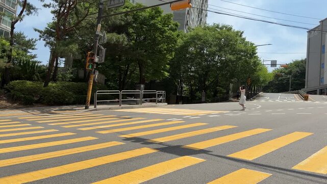 Pedestrian Crossing Yellow Crosswalk as Scooter Turns on Quiet City Street
