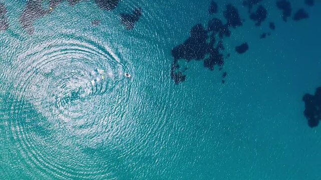 Circular boat wake spreading across turquoise Greek sea