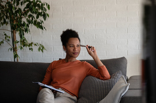 Mature woman thinking about future goals while making notes at home, representing goal setting and personal development