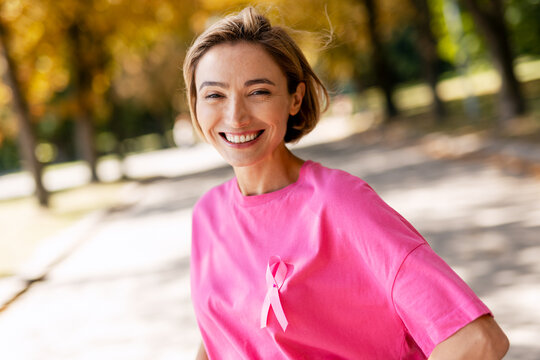 Smiling woman supporting breast cancer awareness in park