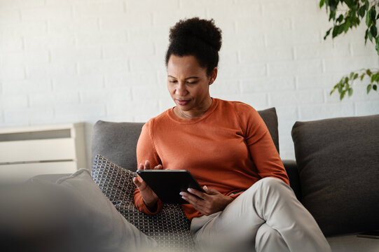 Focused woman using a tablet at home, representing online banking, personal finance and household money management