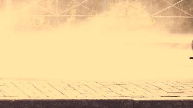 Municipal road sweeper vehicle spraying water onto highway asphalt surface. Dust suppression and cleaning process on urban roadway. Heavy truck with water spray system enhancing traffic safety and air
