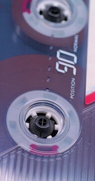 Spinning Cassette Reel Close-Up. Macro view of magnetic tape reel rotating inside a transparent audio cassette with shallow focus.