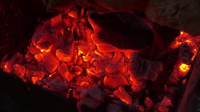 Smoldering firewood glowing inside outdoor grill