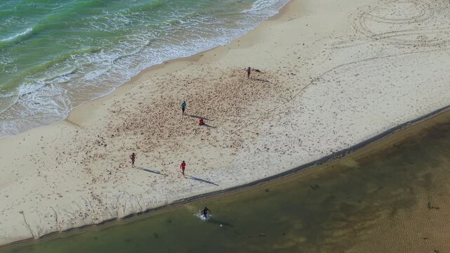 Aerial view of people walking on the sandy beach near the ocean in Morondava, Menabe, Madagascar.
