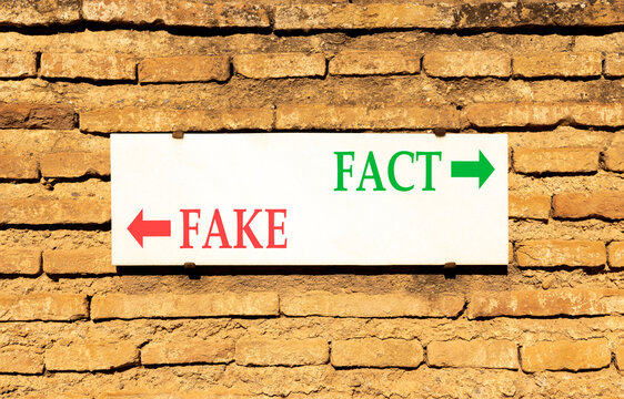 Fact or fake words symbol. Concept words Fake and Fact on beautiful white sign plate. Beautiful brick wall background. Business and fact or fake concept. Copy space.