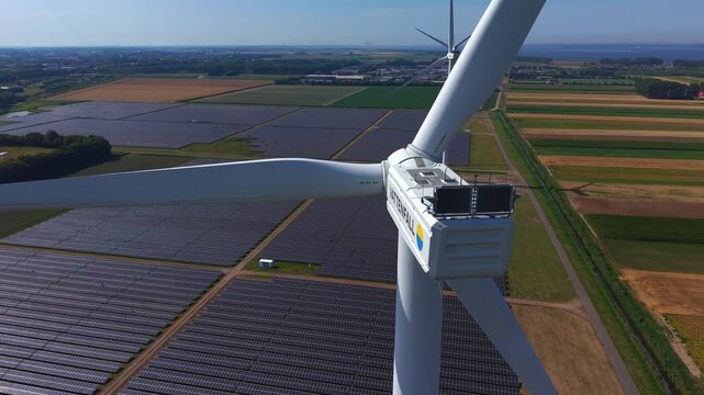 Aerial view of a Vattenfall wind turbine and a large solar farm field in the rural landscape of Middelharnis, South Holland, Netherlands.