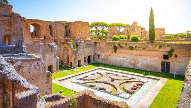 The Fountain of the Pelte is part of the Roman Forum in Rome, Italy. It features a geometric design and is surrounded by ancient ruins and green spaces under bright sunlight.