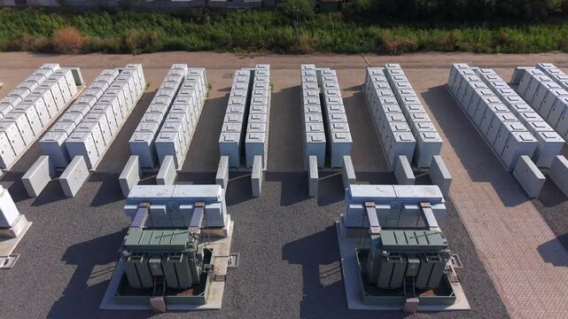 Aerial view of rows of white battery energy storage containers and transformers on a gravel site in Waddinxveen, South Holland, Netherlands.