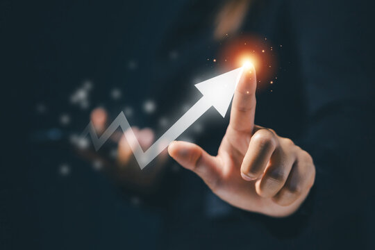 Businesswoman touching glowing upward arrow, symbolizing business growth, financial success, investment strategy, profit increase, market performance, innovation and future opportunity.