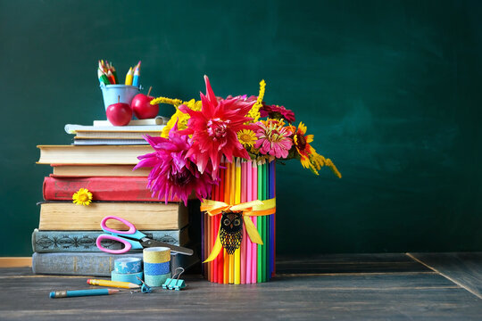 Education, back to school, beginning of the school year, Teacher's day, Knowledge Day, 1 September concept. Stack of learning books, school stationery, apples, flowers bouquet on wooden table.
