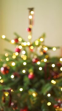 Beautiful out of focus vertical video of a decorated Christmas tree with warm shimmering fairy lights creating a magical festive bokeh effect.