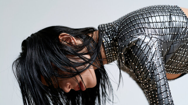 Close-up of a woman in a rhinestone-adorned bodysuit bending backward against a plain white background, faceless dance and fitness concept, with copy space