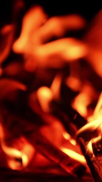 Wood burns out in the campfire. Blurred image of the bonfire in the darkness. Close up. Vertical video