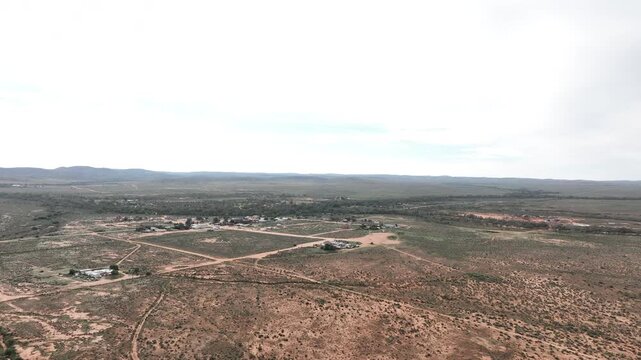 Sweeping aerial drone panorama across Silverton and its sparse network of roads and buildings surrounded by the vast landscape near Broken Hill.