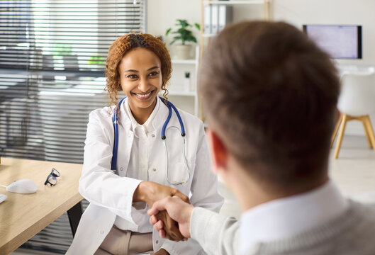 Doctor and patient handshake during consultation appointment. In a bright clinic, a doctor shares diagnosis, builds trust and offers support in healthcare. Concept of professional patient care.