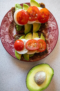 Hirtshals, Denmark A healthy open-faced sandwich with dark bread, avocado, tomato and eggs.