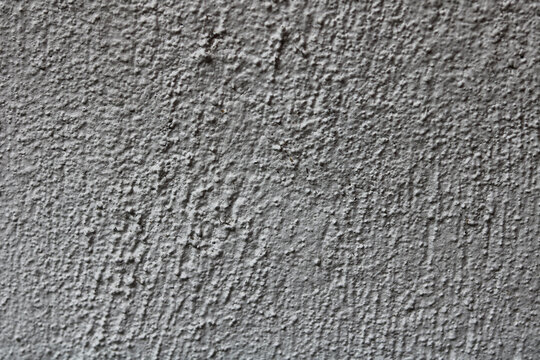 A neutral grey rough plaster or stucco wall surface.