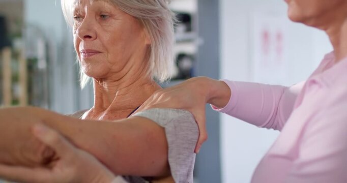 Senior female patient extending right arm at rehab clinic after clinician hand placement and cues