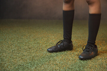 Woman standing on turf at studio wearing black knee-high socks and untied soccer shoes, copy space © wavebreak3