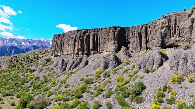Aerial view of columnar clay cliff formations and weathered soil slopes under a clear blue sky along the S101 Highway in Xinjiang, China