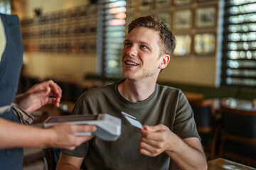 Young man paying for restaurant meal with credit card