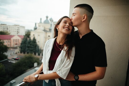 Young couple sharing an affectionate kiss on city balcony
