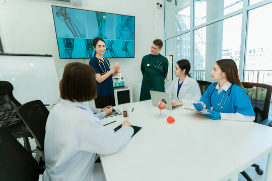 Group of diverse medical doctors and specialists discussing anatomical models during clinical seminar